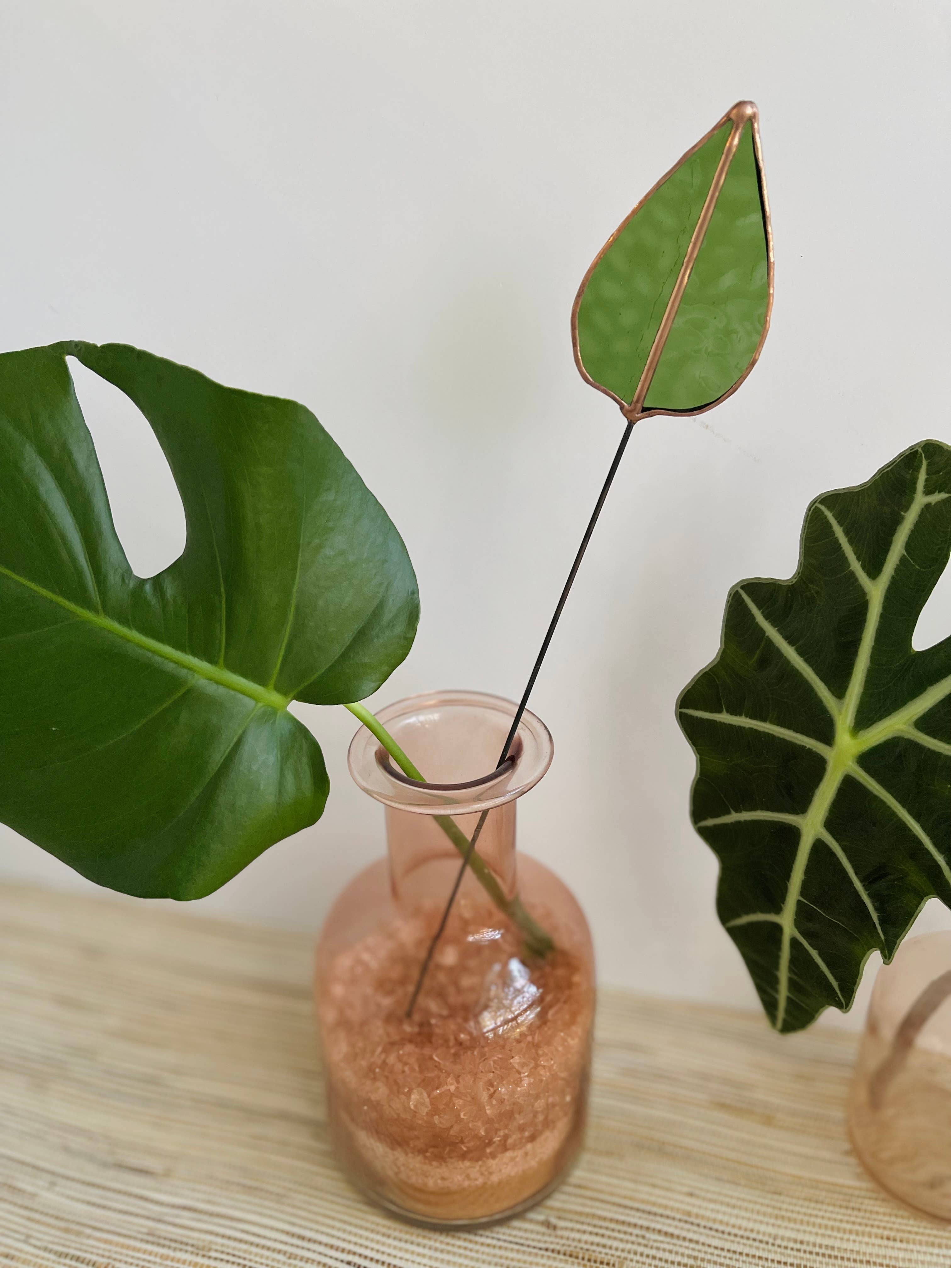 Bring a pop of color and artistry to your home with this handcrafted stained glass mulberry leaf stem by Samara Designs Studio. This stem is made from transparent earthy green stained glass with copper accents, evoking the solid, grounding tones of nature. Each piece is carefully handmade to create a lasting botanical accent that will never wilt or fade.