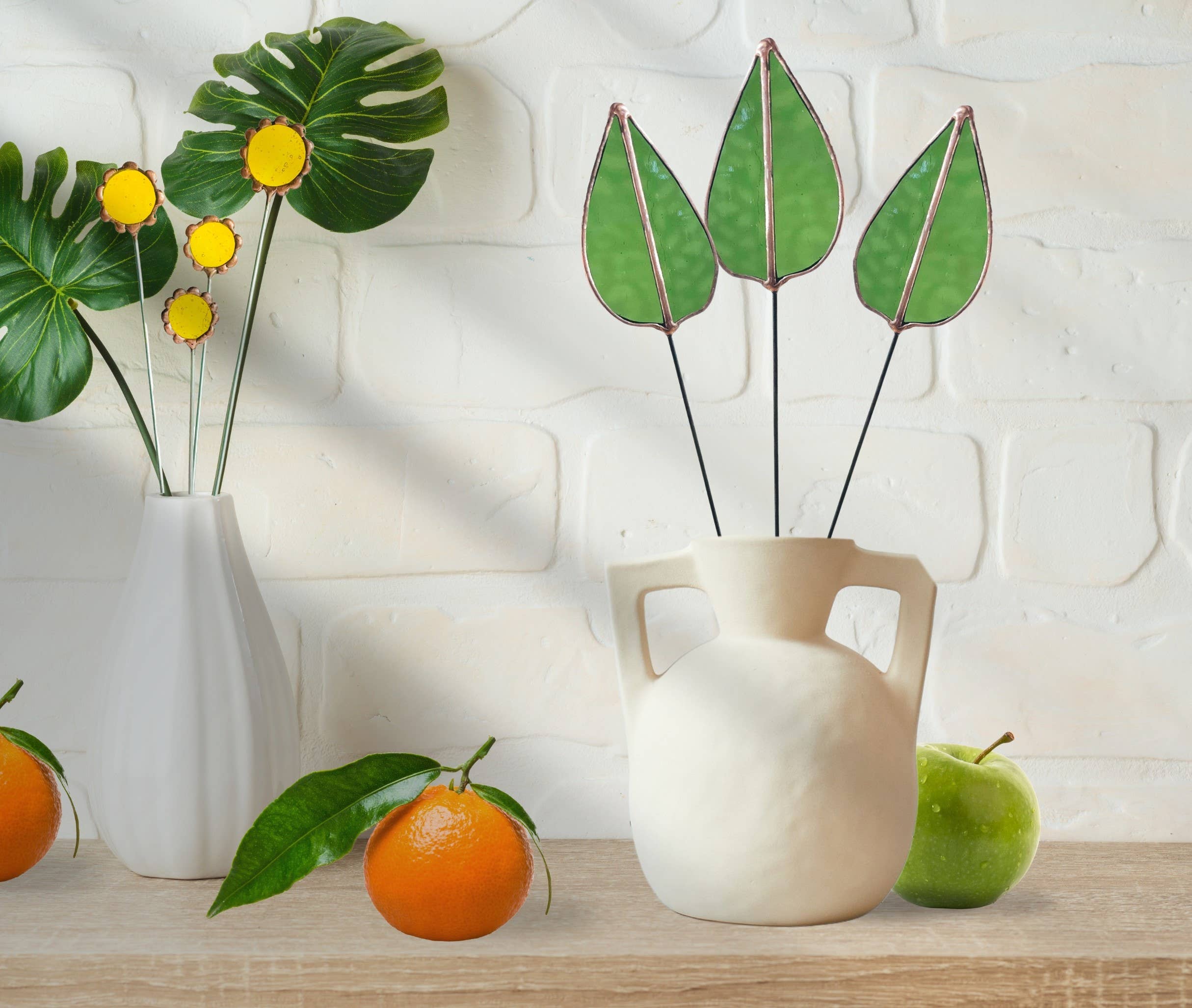 Bring a pop of color and artistry to your home with this handcrafted stained glass mulberry leaf stem by Samara Designs Studio. This stem is made from transparent earthy green stained glass with copper accents, evoking the solid, grounding tones of nature. Each piece is carefully handmade to create a lasting botanical accent that will never wilt or fade.