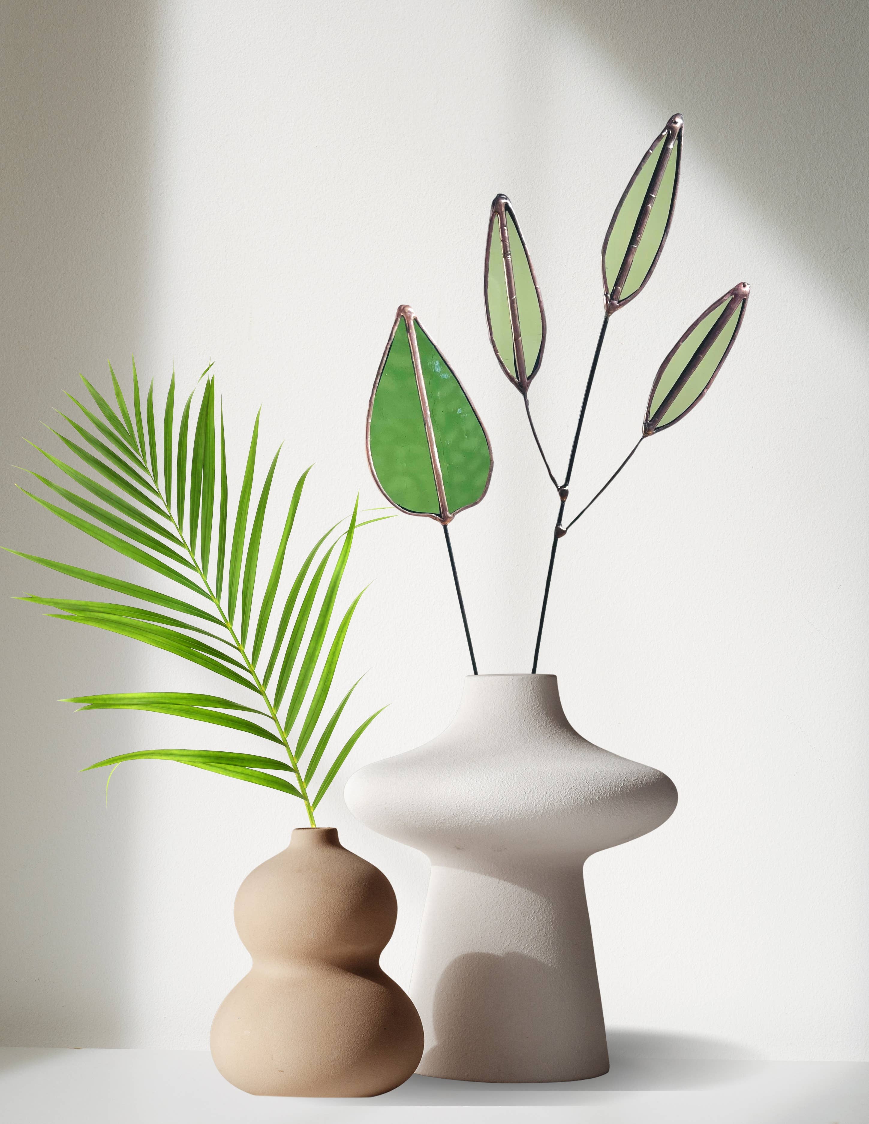 Bring a pop of color and artistry to your home with this handcrafted stained glass mulberry leaf stem by Samara Designs Studio. This stem is made from transparent earthy green stained glass with copper accents, evoking the solid, grounding tones of nature. Each piece is carefully handmade to create a lasting botanical accent that will never wilt or fade.