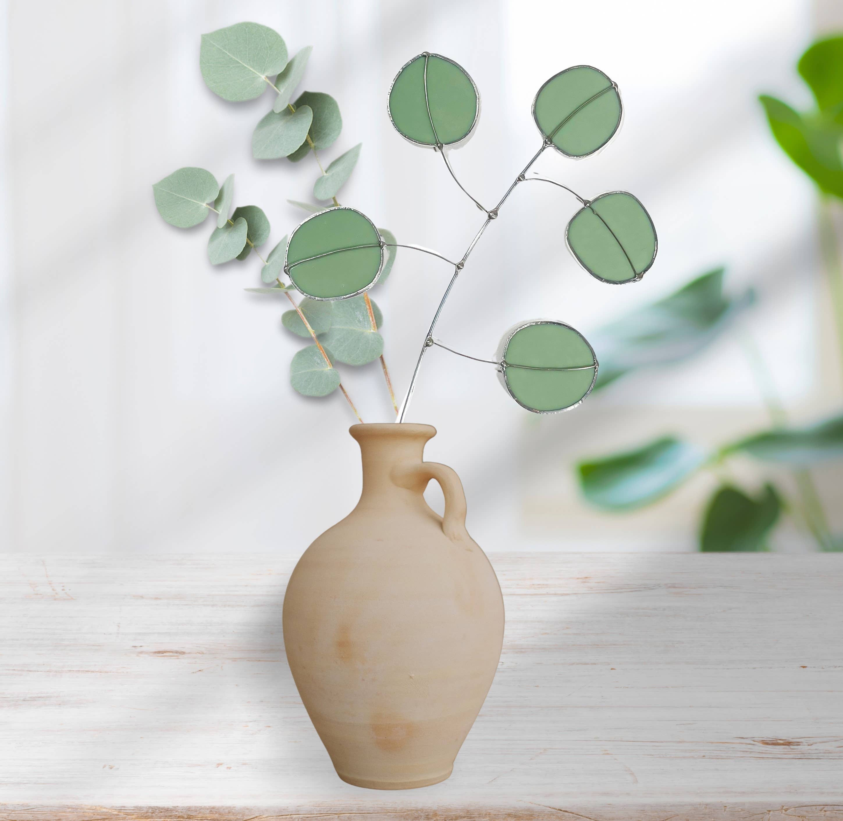 Bring a pop of color and artistry to your home with this handcrafted stained glass silver dollar eucalyptus stem by Samara Designs Studio. This stem is made from beautiful celadon green stained glass, carefully cut and assembled by hand to create a lasting botanical accent that will never wilt or fade.