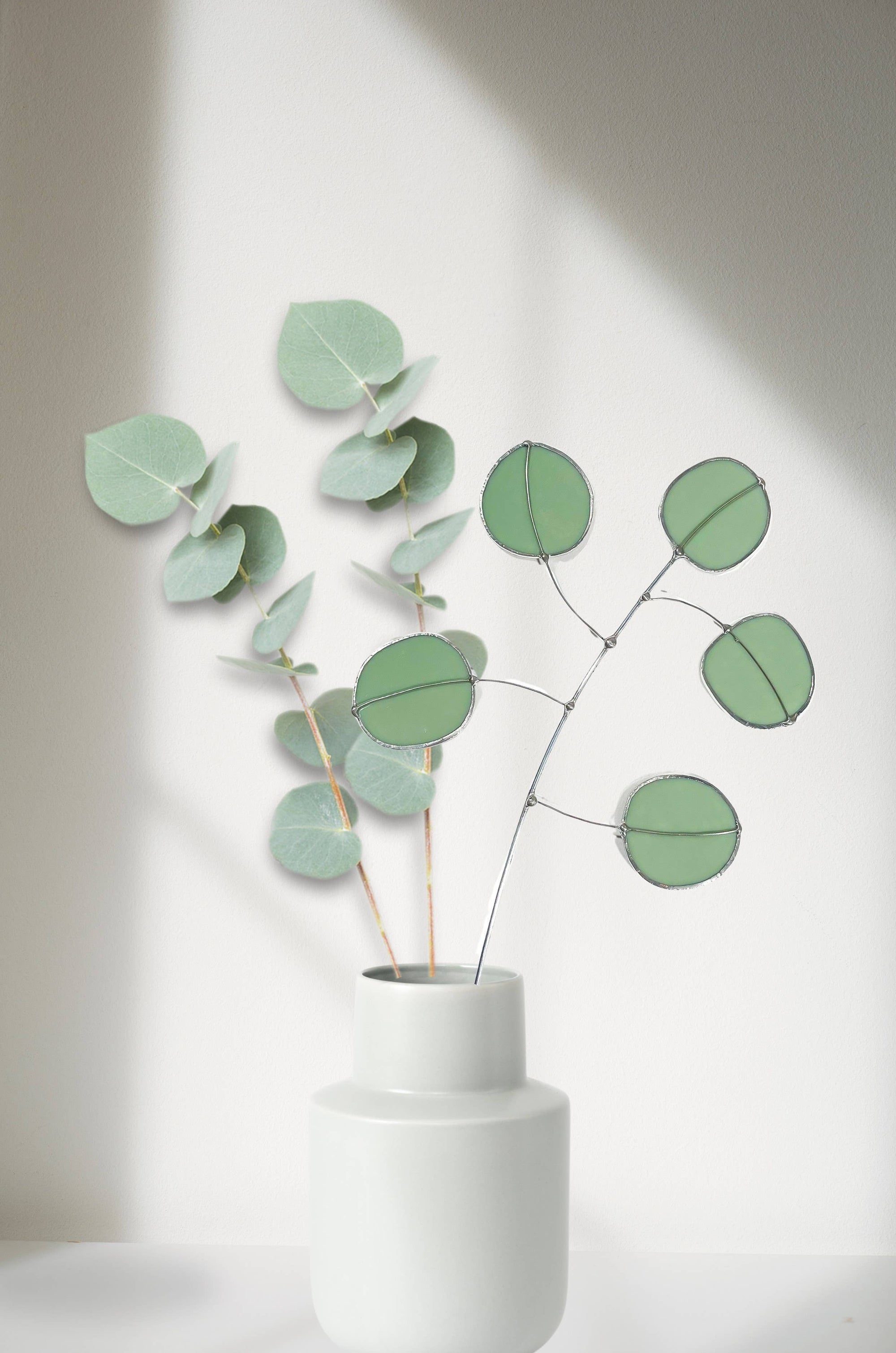 Bring a pop of color and artistry to your home with this handcrafted stained glass silver dollar eucalyptus stem by Samara Designs Studio. This stem is made from beautiful celadon green stained glass, carefully cut and assembled by hand to create a lasting botanical accent that will never wilt or fade.