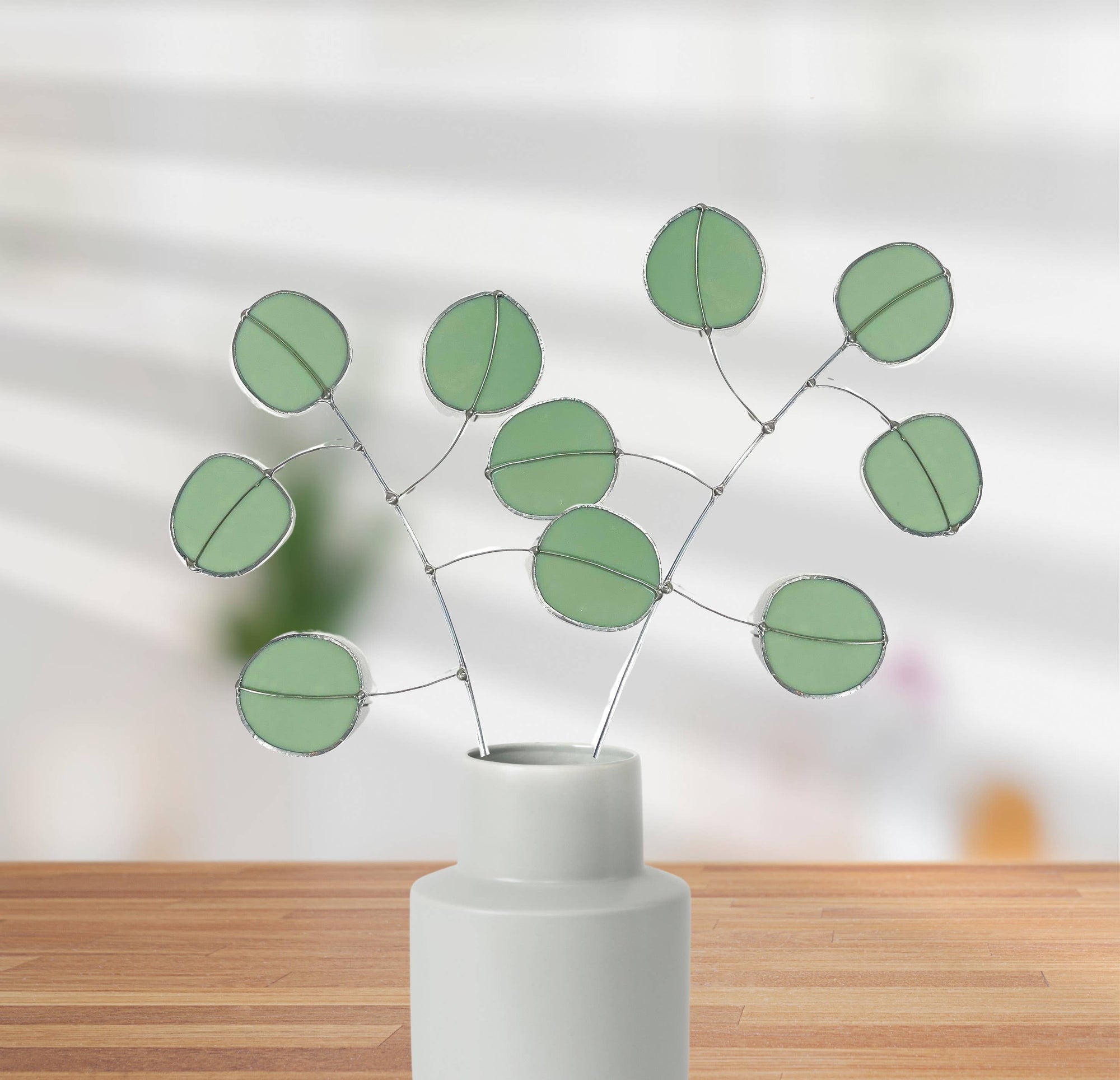 Bring a pop of color and artistry to your home with this handcrafted stained glass silver dollar eucalyptus stem by Samara Designs Studio. This stem is made from beautiful celadon green stained glass, carefully cut and assembled by hand to create a lasting botanical accent that will never wilt or fade.