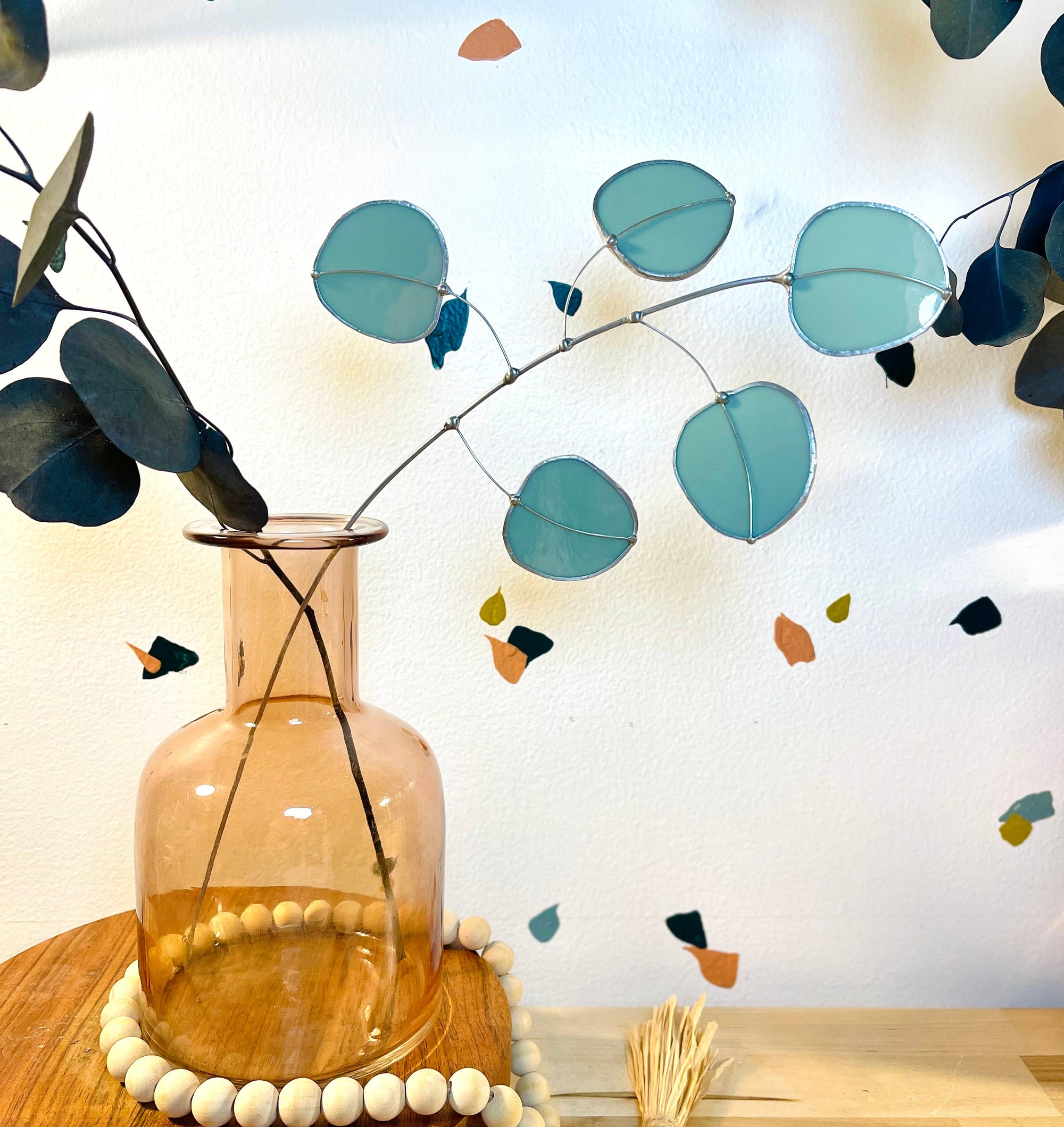 Bring a pop of color and artistry to your home with this handcrafted stained glass silver dollar eucalyptus stem by Samara Designs Studio. This stem is made from beautiful celadon green stained glass, carefully cut and assembled by hand to create a lasting botanical accent that will never wilt or fade.