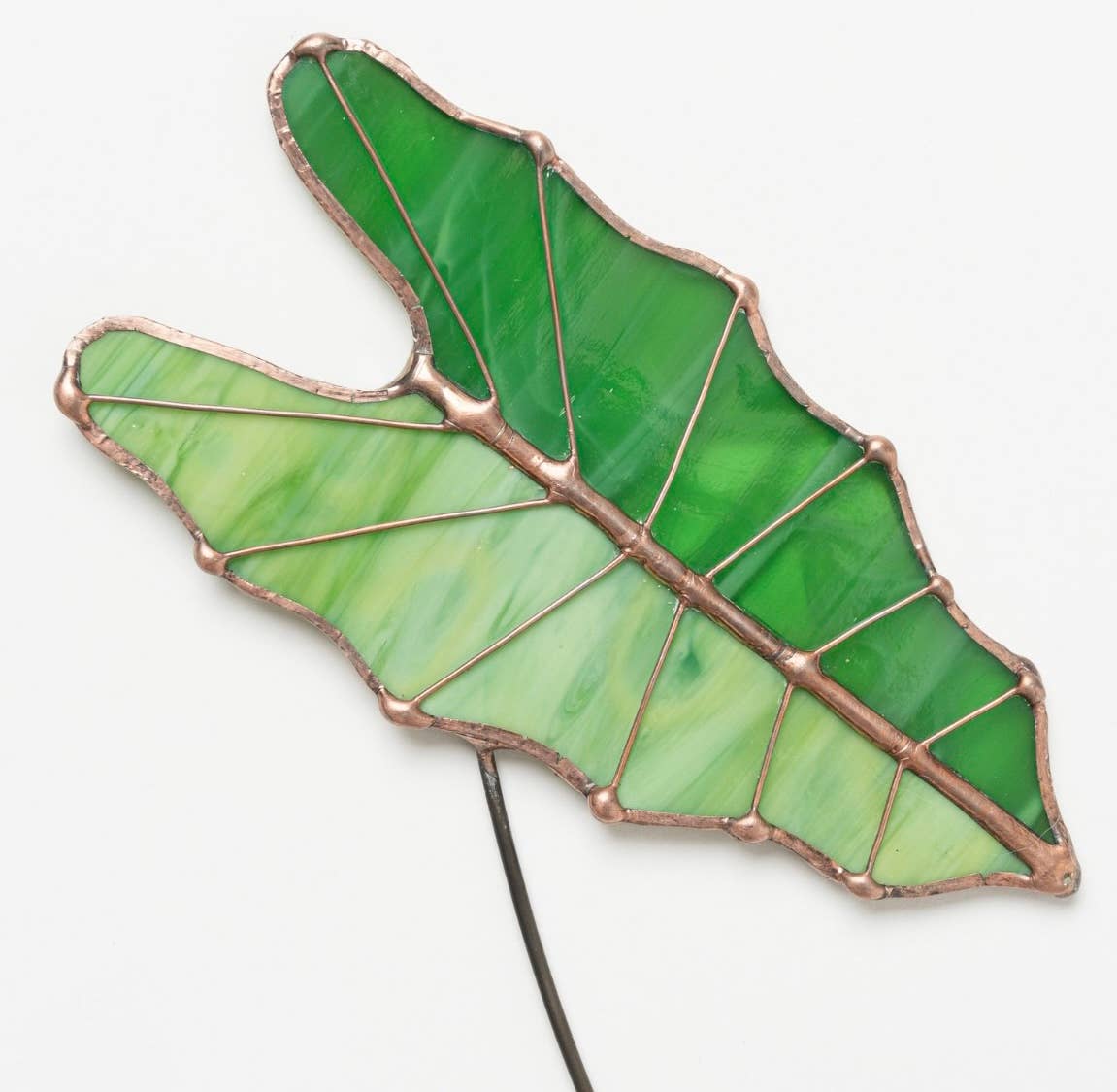 Bring a pop of color and artistry to your home with this handcrafted stained glass tropical green Alocasia leaf by Samara Designs Studio. This artistic interpretation captures the unique shape of the Alocasia leaf in lasting stained glass that will never wilt or fade. Each leaf is carefully handmade using stained glass and galvanized steel wire for a durable botanical accent.