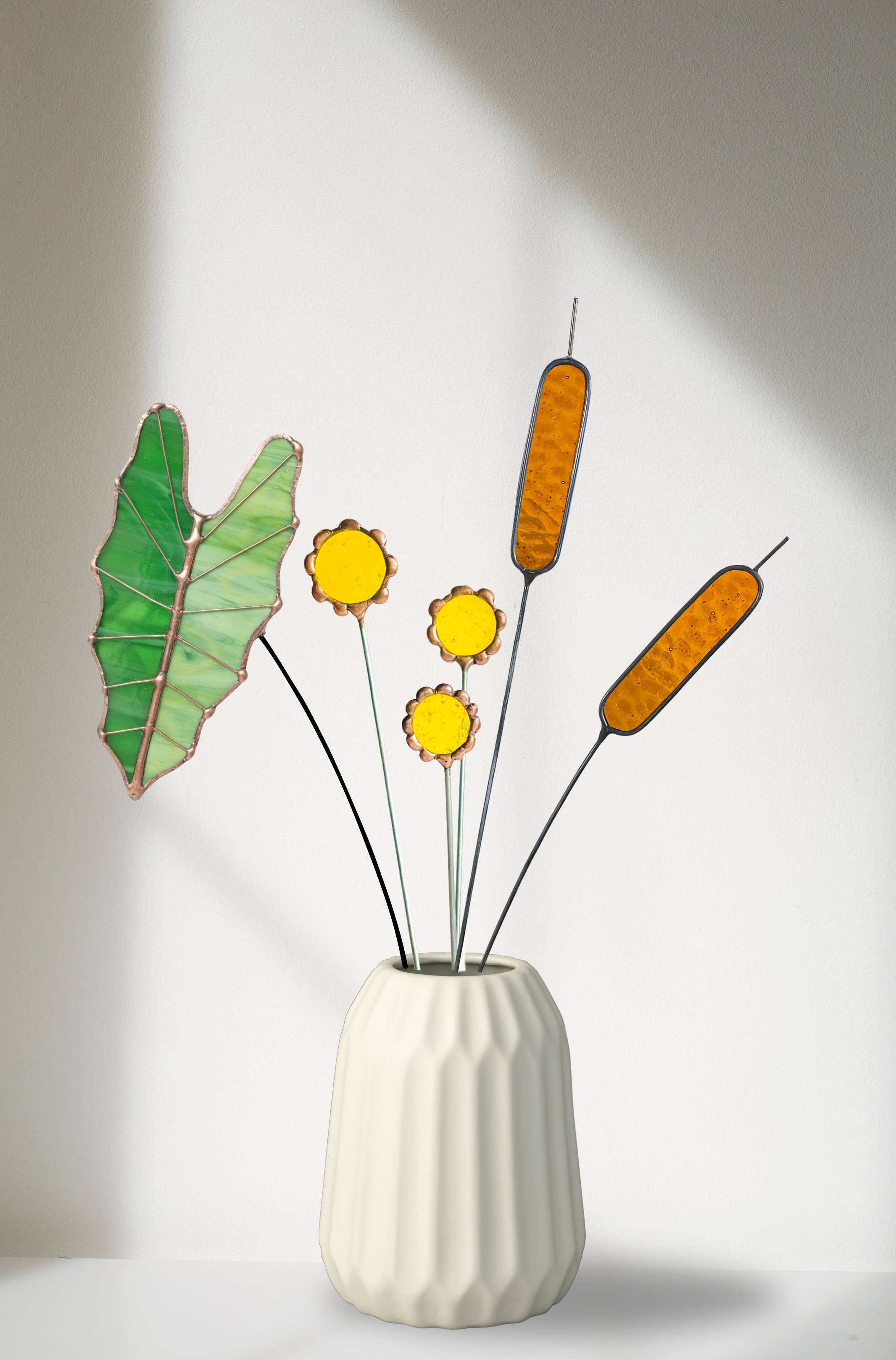 Bring a pop of color and artistry to your home with this handcrafted stained glass tropical green Alocasia leaf by Samara Designs Studio. This artistic interpretation captures the unique shape of the Alocasia leaf in lasting stained glass that will never wilt or fade. Each leaf is carefully handmade using stained glass and galvanized steel wire for a durable botanical accent.