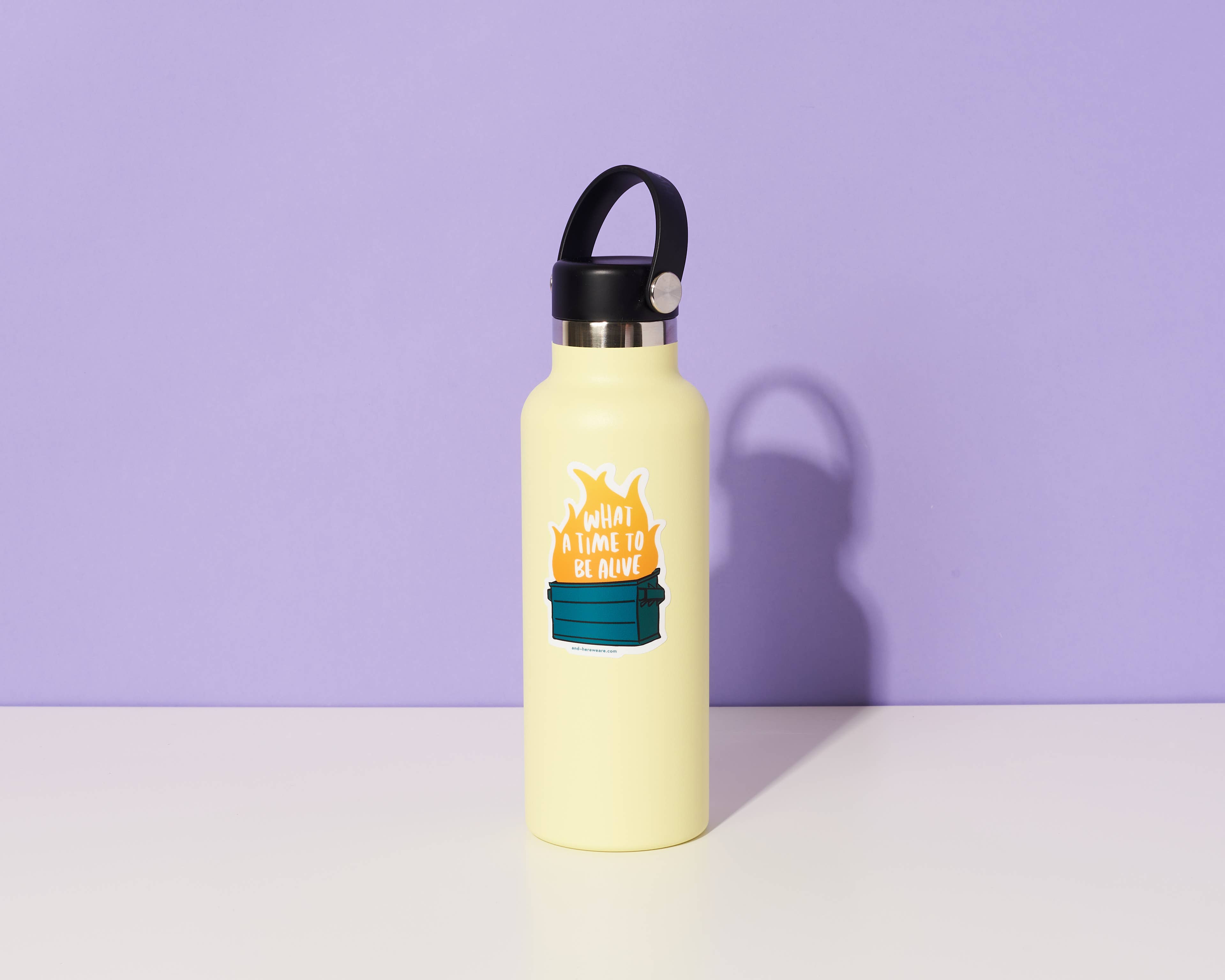 Yellow water bottle with a black lid on a white surface against a purple background