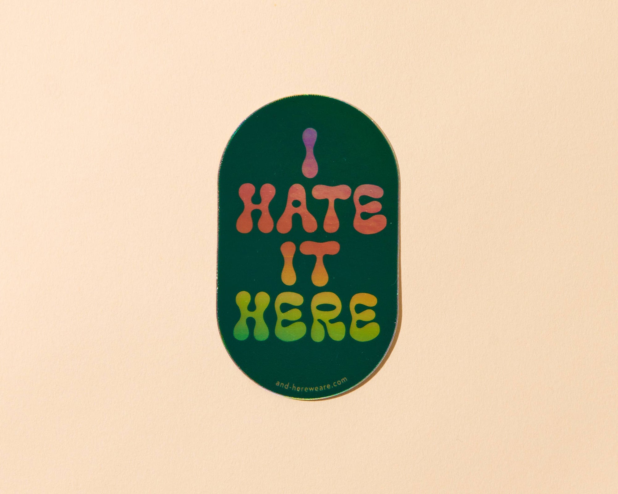 Sticker with 'I HATE IT HERE' text on a beige background