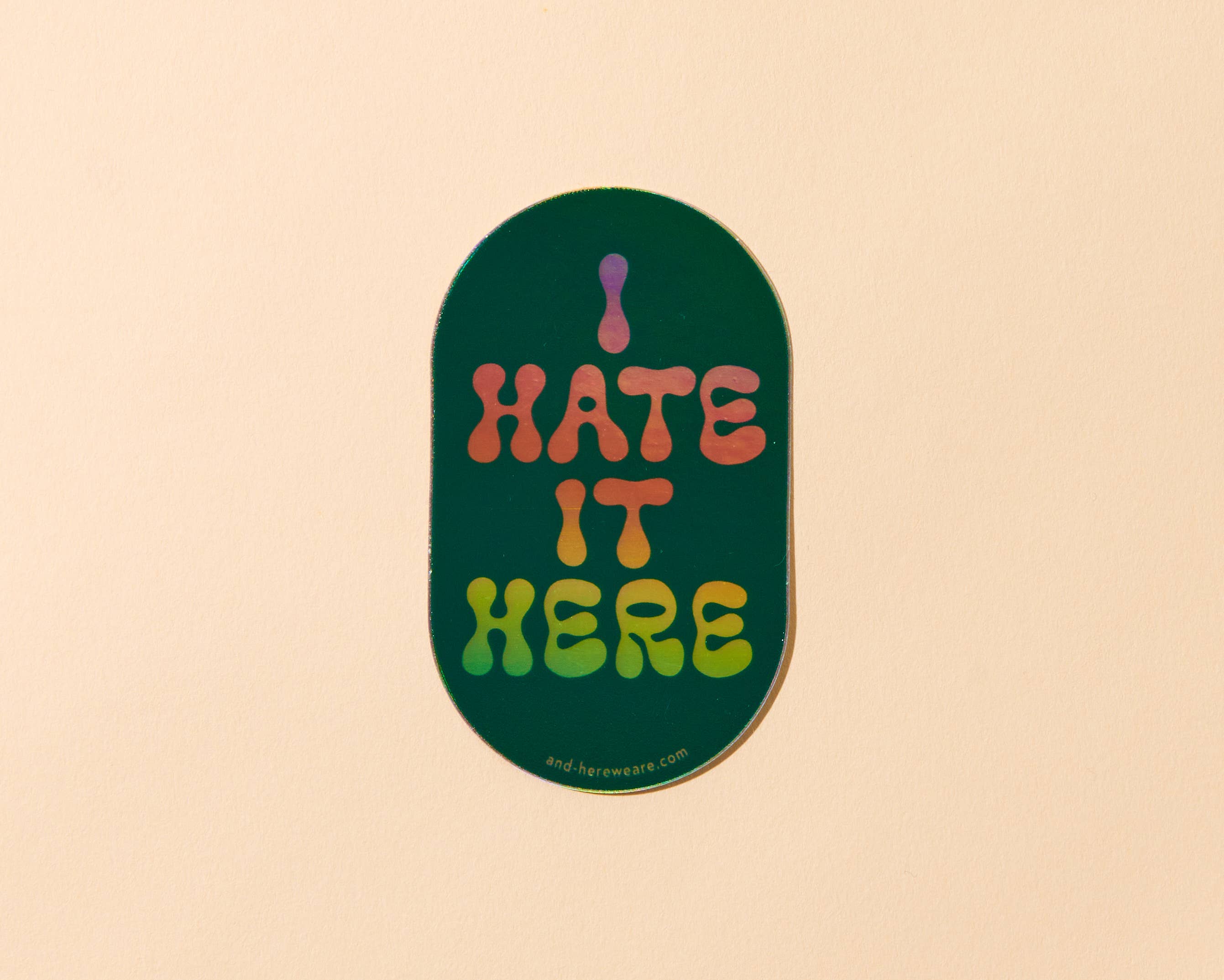 Sticker with 'I HATE IT HERE' text on a beige background
