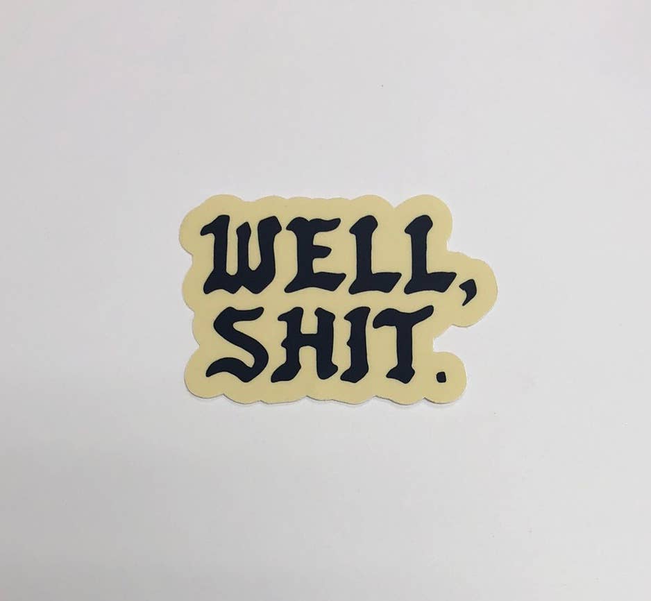 Beige sticker with black text 'WELL, SHIT.' on a light gray background