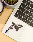 Laptop with a sticker of an orca whale and the text 'KILLING IT' on a beige surface.
