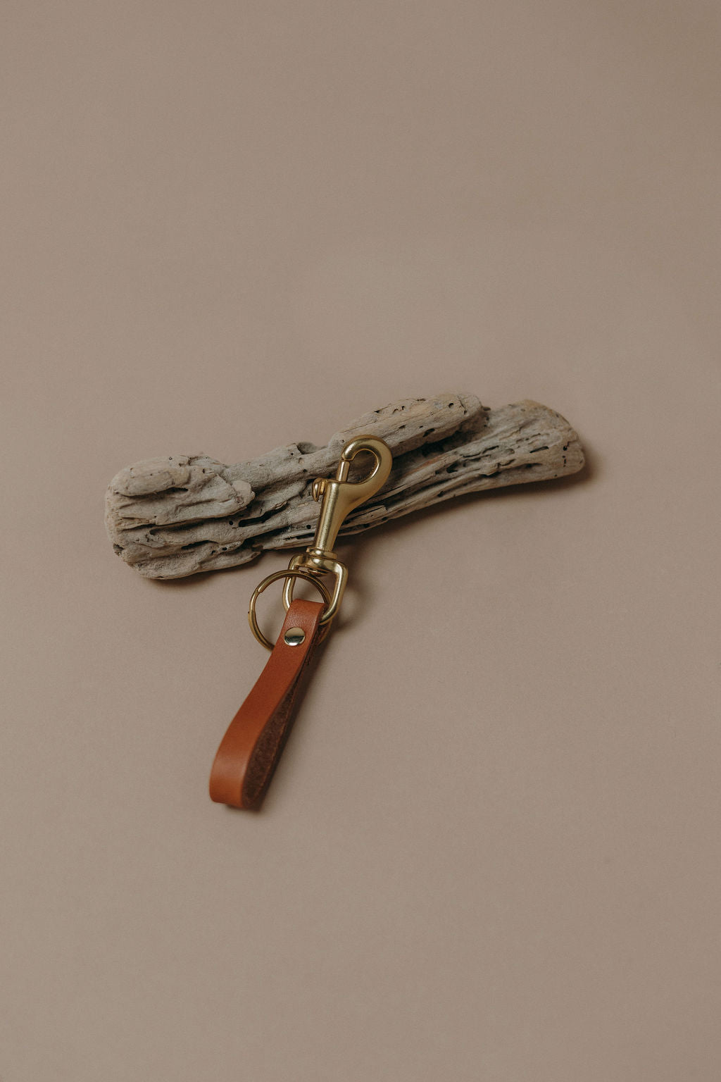 Tan colored leather keychain with a brass swivel clip and a solid brass rivet.