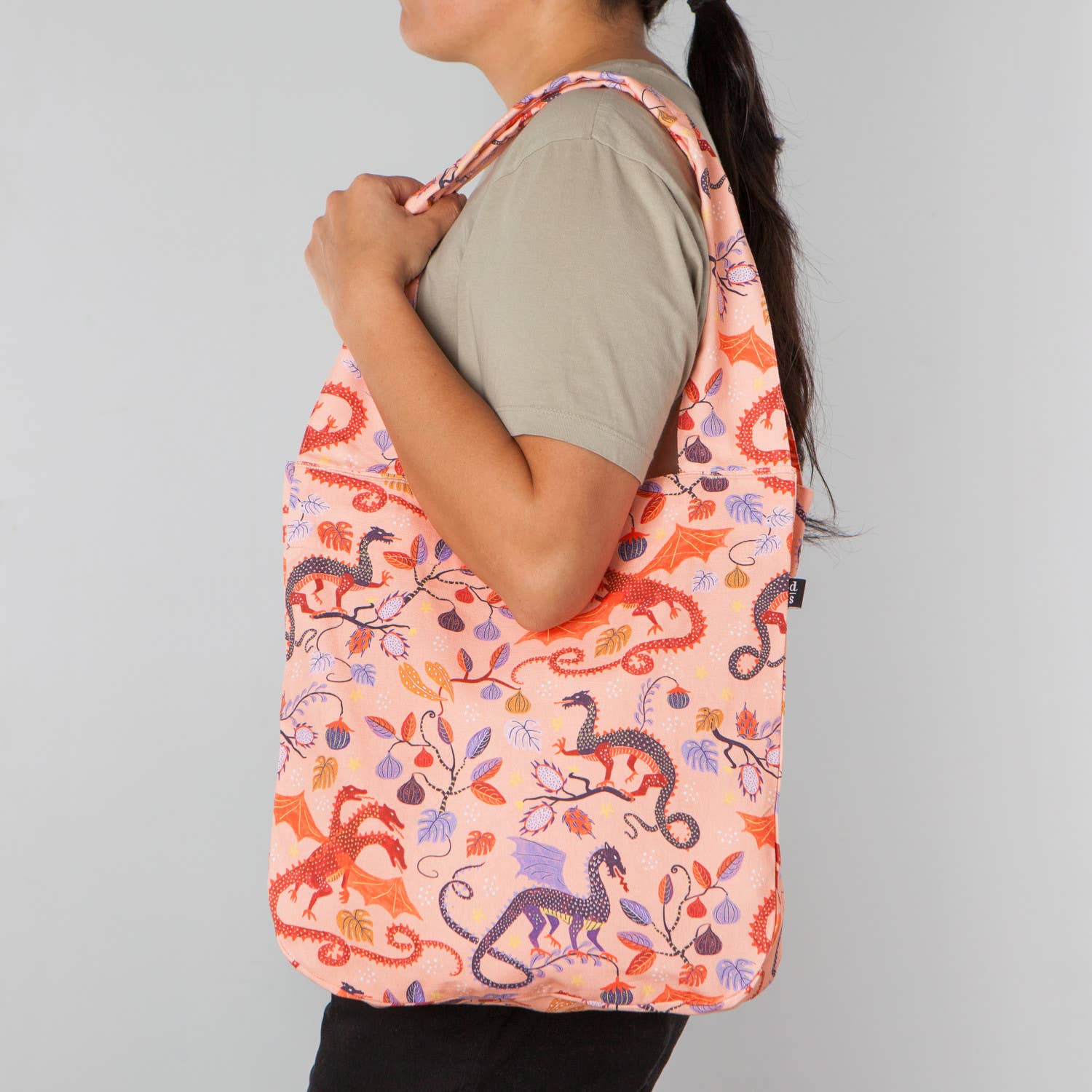 The Ember Tote Bag by Danica Studio features a square shape, wide handles &amp; an inside pocket. Adorned with a bold dragon print, it’s a stylish, durable everyday tote.