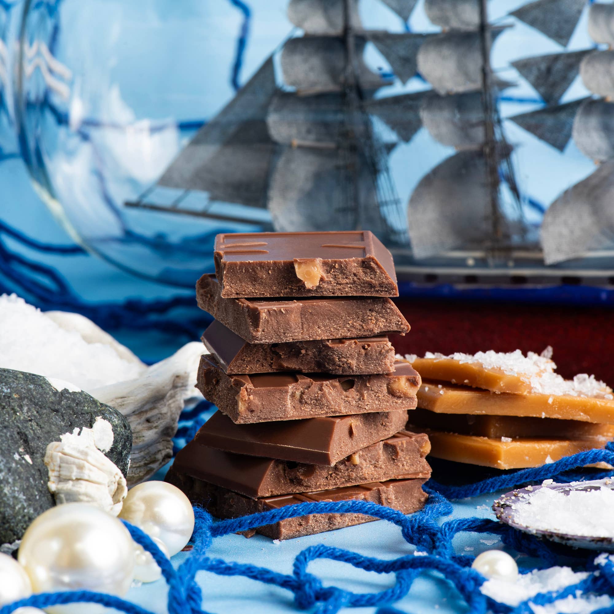 Stack of chocolate bars with a ship and nautical elements in the background