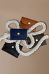 Uniform snap wallets in tan, indigo, olive and black on a white rope and tan background