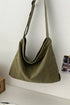 Olive canvas crossbody shoulder bag hanging on a white wall