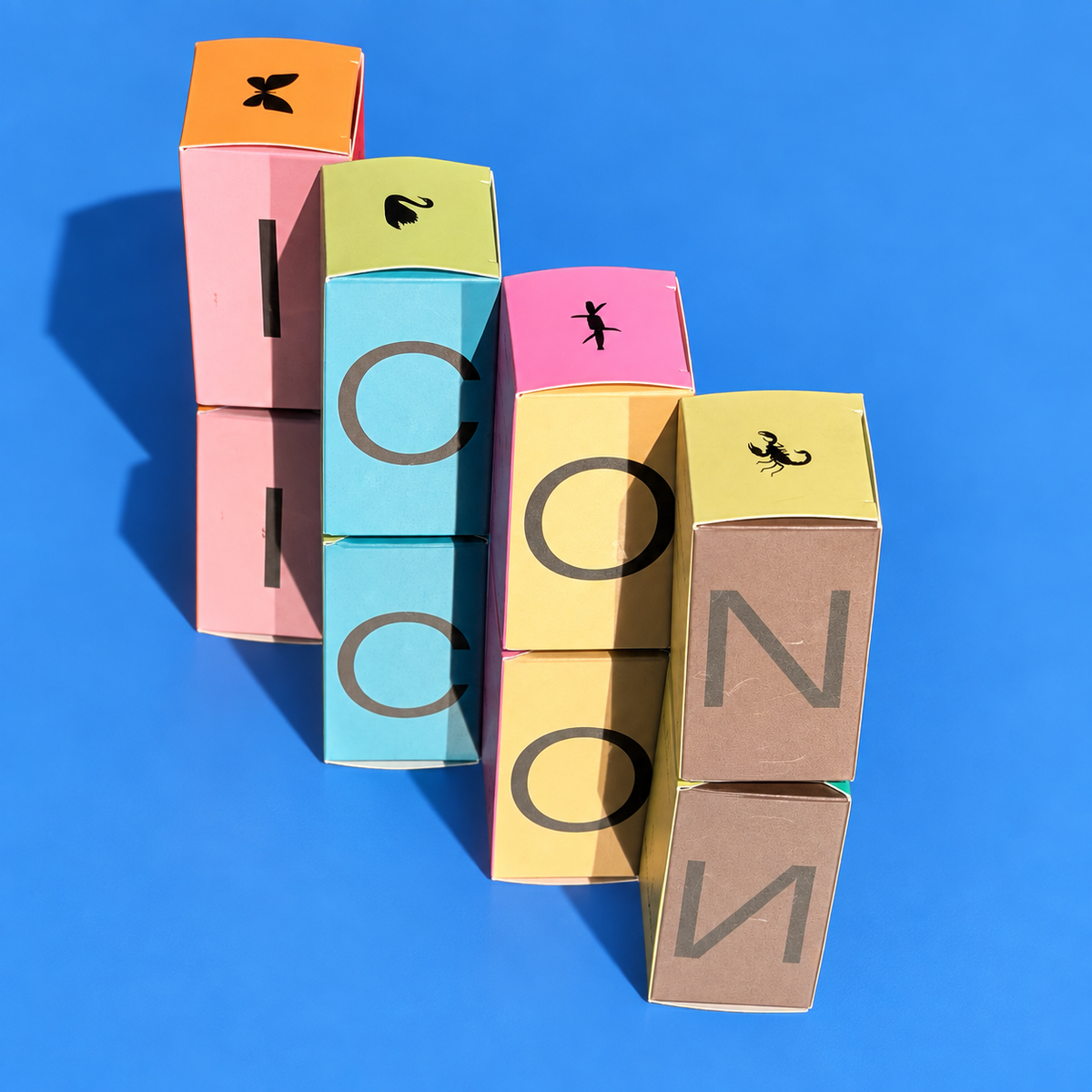 Stacked Icons perfume boxes spelling ICON on a blue background