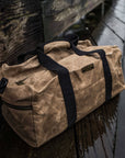Waxed canvas duffel bag with webbing straps, padded handle and brass zipper