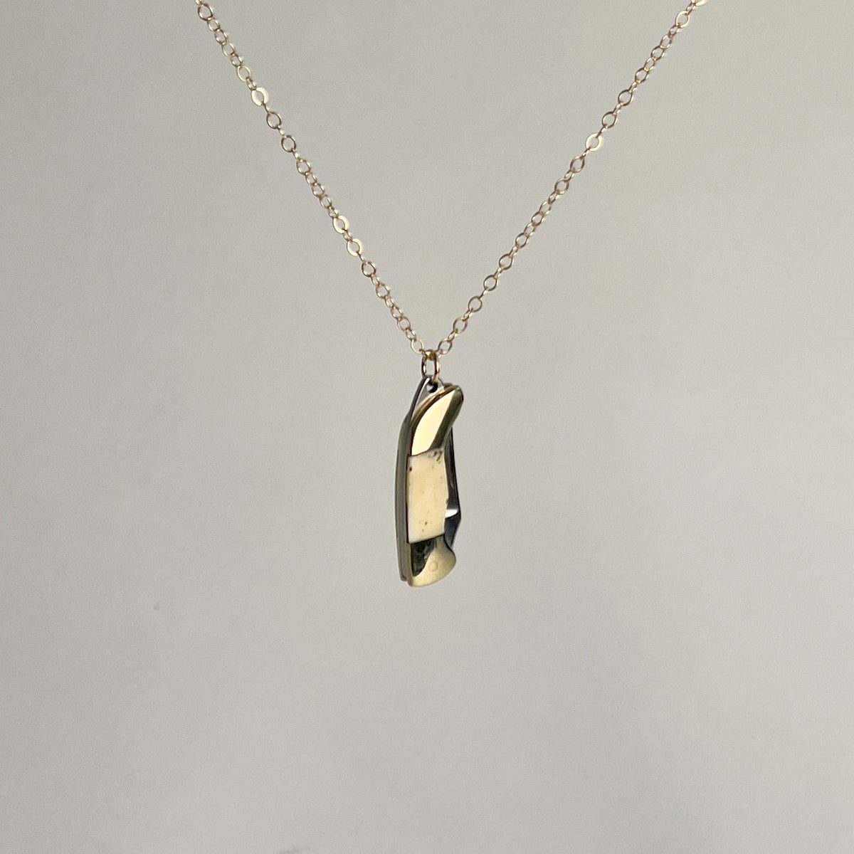 Mini bone-handled pocket knife pendant, closed, hanging from a gold-filled chain