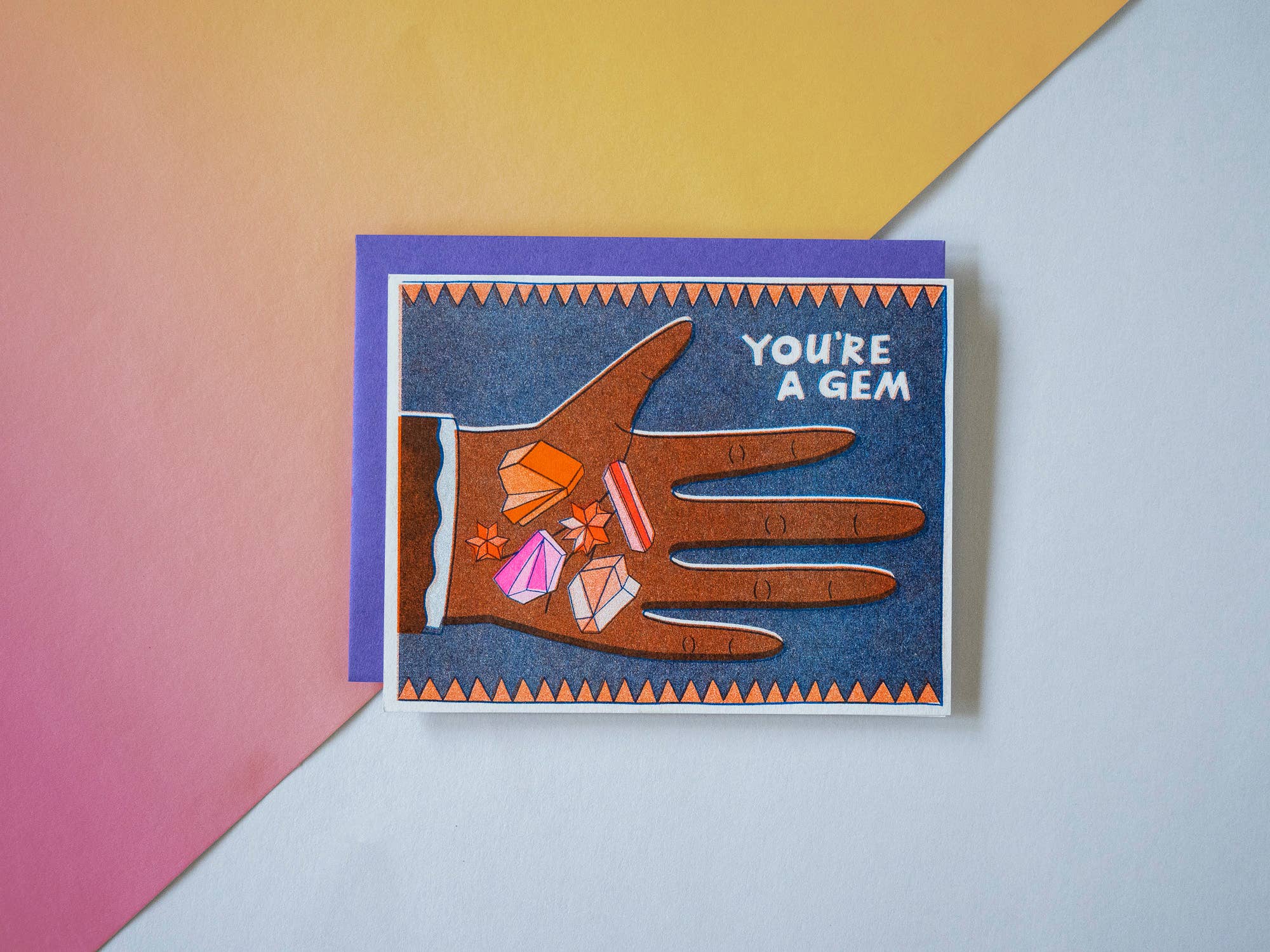 Greeting card with a hand holding gemstones and 'You're a Gem' text on a colorful background