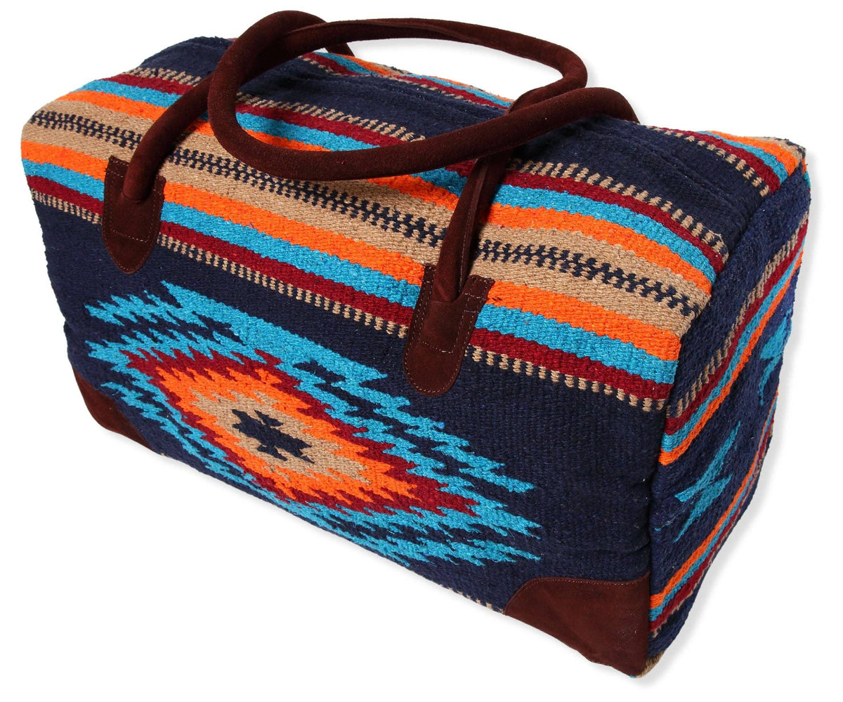 Large navy handwoven duffel bag with turquoise, orange and red Southwest diamond pattern and brown suede handles, on a white background