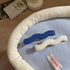 Blue and cream wavy hair clips on a blue cloth with a white padded tray edge
