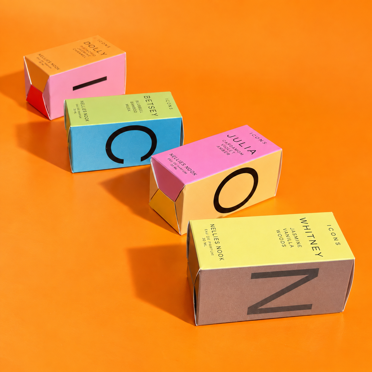 Icons perfume boxes for Dolly, Betsey, Julia and Whitney laid out to spell ICON on an orange background