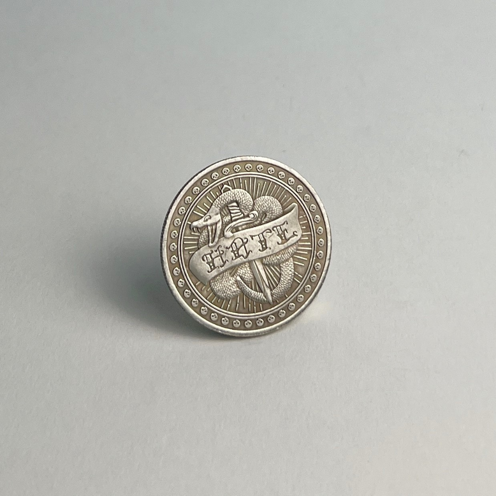 Silver-toned coin showing the HATE side, standing on a light gray background
