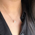 Woman in a black top wearing a fine chain with a small white rough gemstone