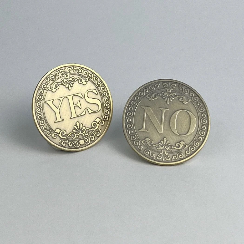 Two bronze-finished decision coins, one showing YES and one showing NO, on a light gray background