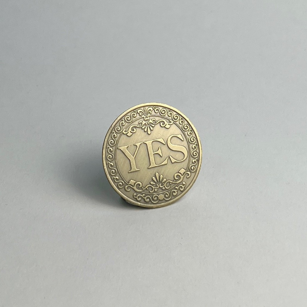 Bronze-finished coin showing YES, standing on a light gray background