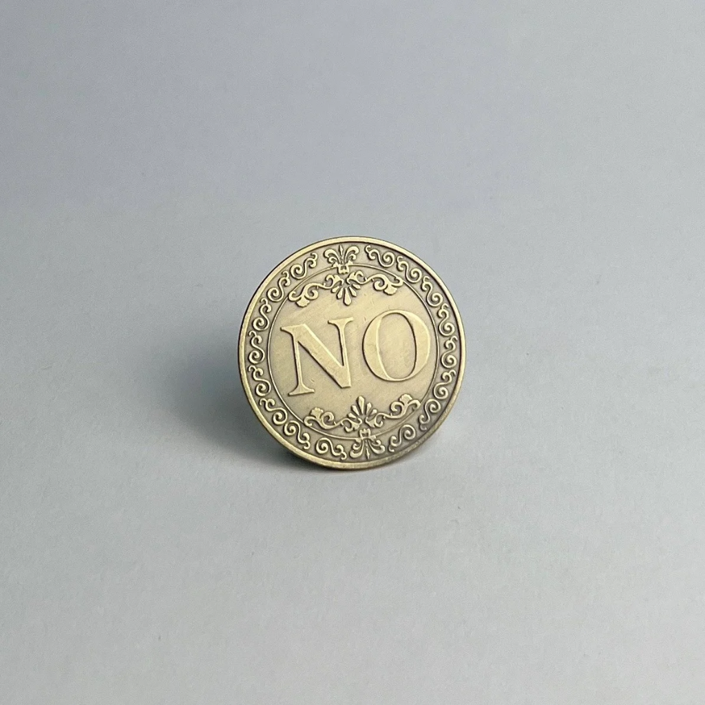 Bronze-finished coin showing NO, standing on a light gray background