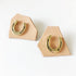 Two gold horseshoe lapel pins on tan leather backing cards on a white surface