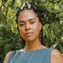 Woman with braided hair in a blue sleeveless top wearing red jade drop earrings