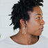 Profile of a model wearing a gold squiggle-shaped earring