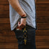Man in a gray T-shirt and jeans wearing a leather bracelet, keys clipped at his pocket